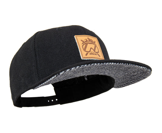 Ski Snapback Cap von Jumping Bird - Modell Kitzbühel in schwarz/Hahnentritt mit Badge in Lederoptik und Logo-Stick seitlich