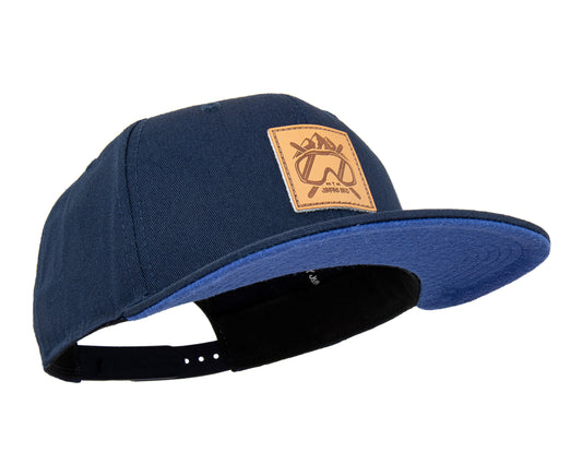 Ski Snapback Cap von Jumping Bird - Modell Ischgl in dunkelblau/blau mit Badge in Lederoptik und Logo-Stick seitlich