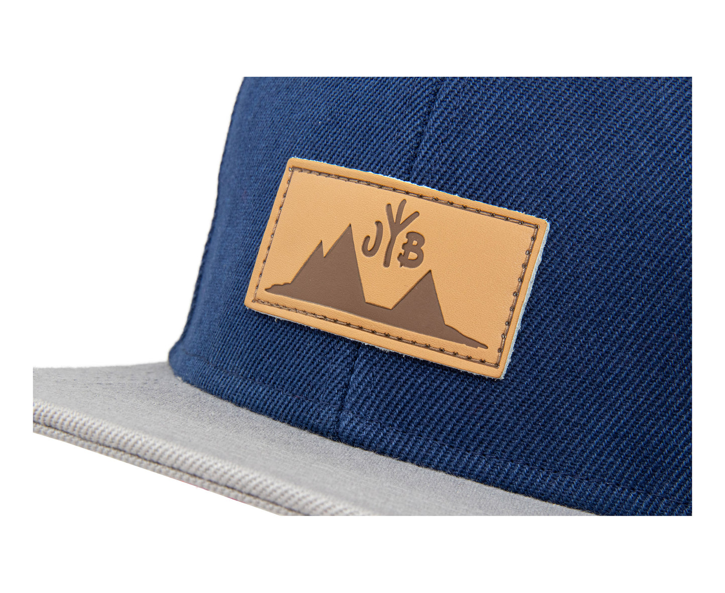 Snapback-Cap von Jumping Bird in Blau-Grau mit geprägtem Lederoptik-Patch vorn und seitlichem Logostick