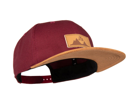 Snapback-Cap von Jumping Bird in Bordeaux-Braun mit geprägtem Lederoptik-Patch vorn und seitlichem Logostick
