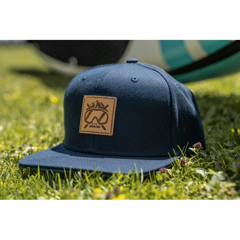 Ski Snapback Cap von Jumping Bird - Modell Ischgl in dunkelblau/blau mit Badge in Lederoptik und Logo-Stick seitlich