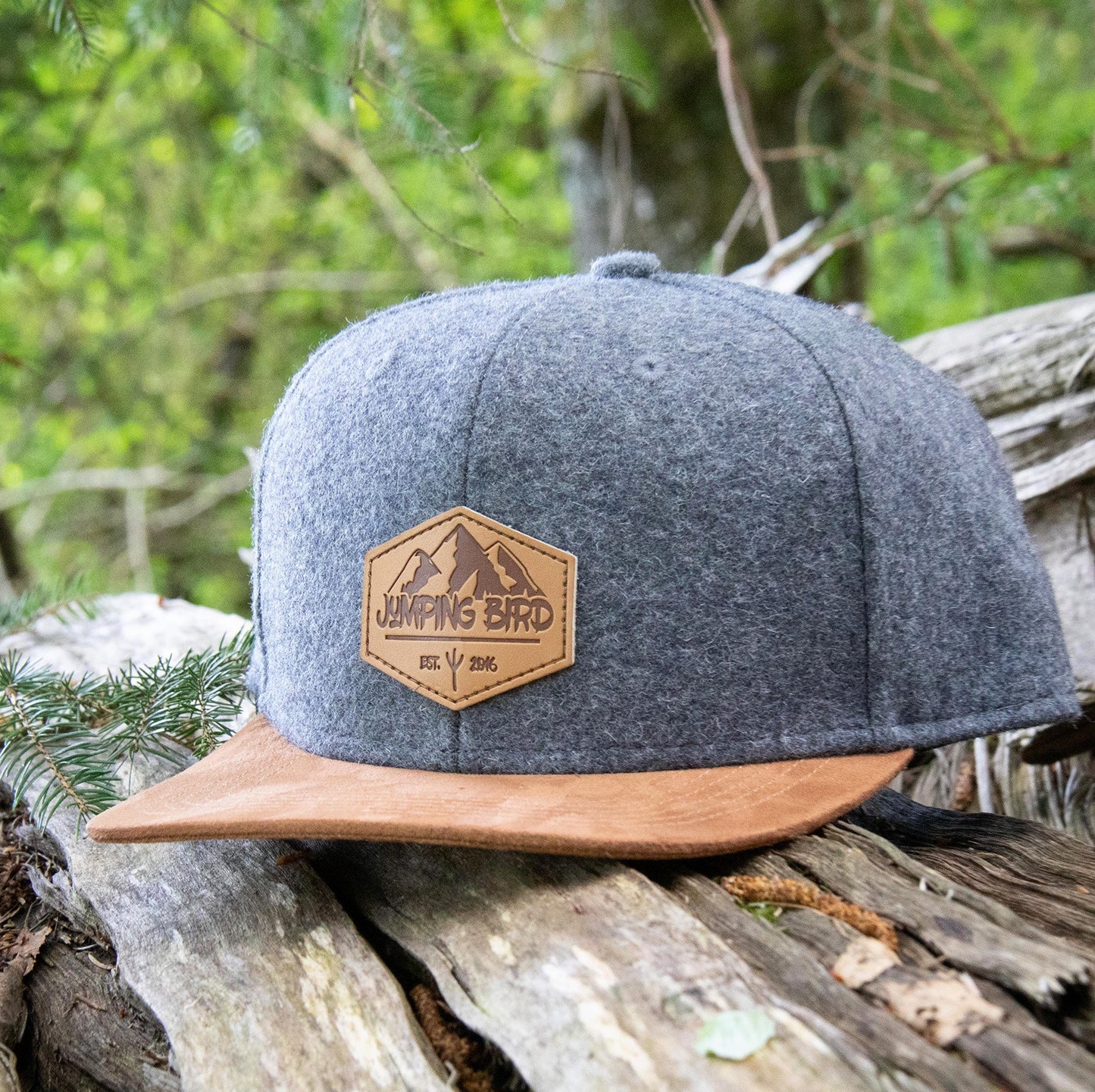 Filz-Snapback von Jumping Bird in Steingrau-Braun mit geprägtem Lederoptik-Patch vorn und seitlichem Logostick