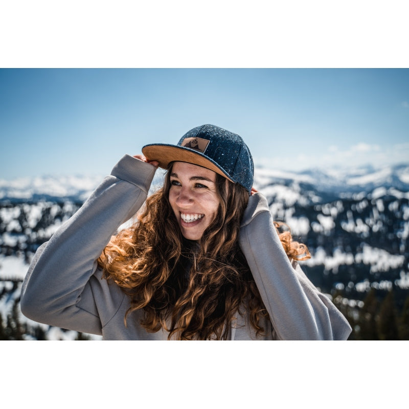 Snapback-Cap von Jumping Bird in Anthrazitblau meliert mit geprägtem Lederoptik-Patch vorn und seitlichem Logostick