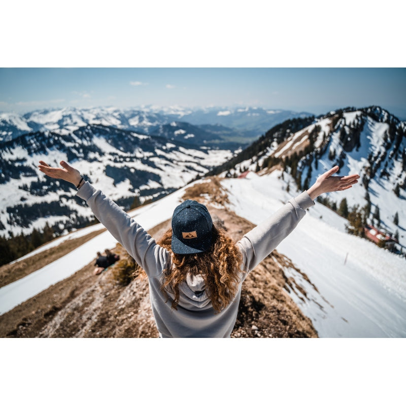 Snapback-Cap von Jumping Bird in Anthrazitblau meliert mit geprägtem Lederoptik-Patch vorn und seitlichem Logostick