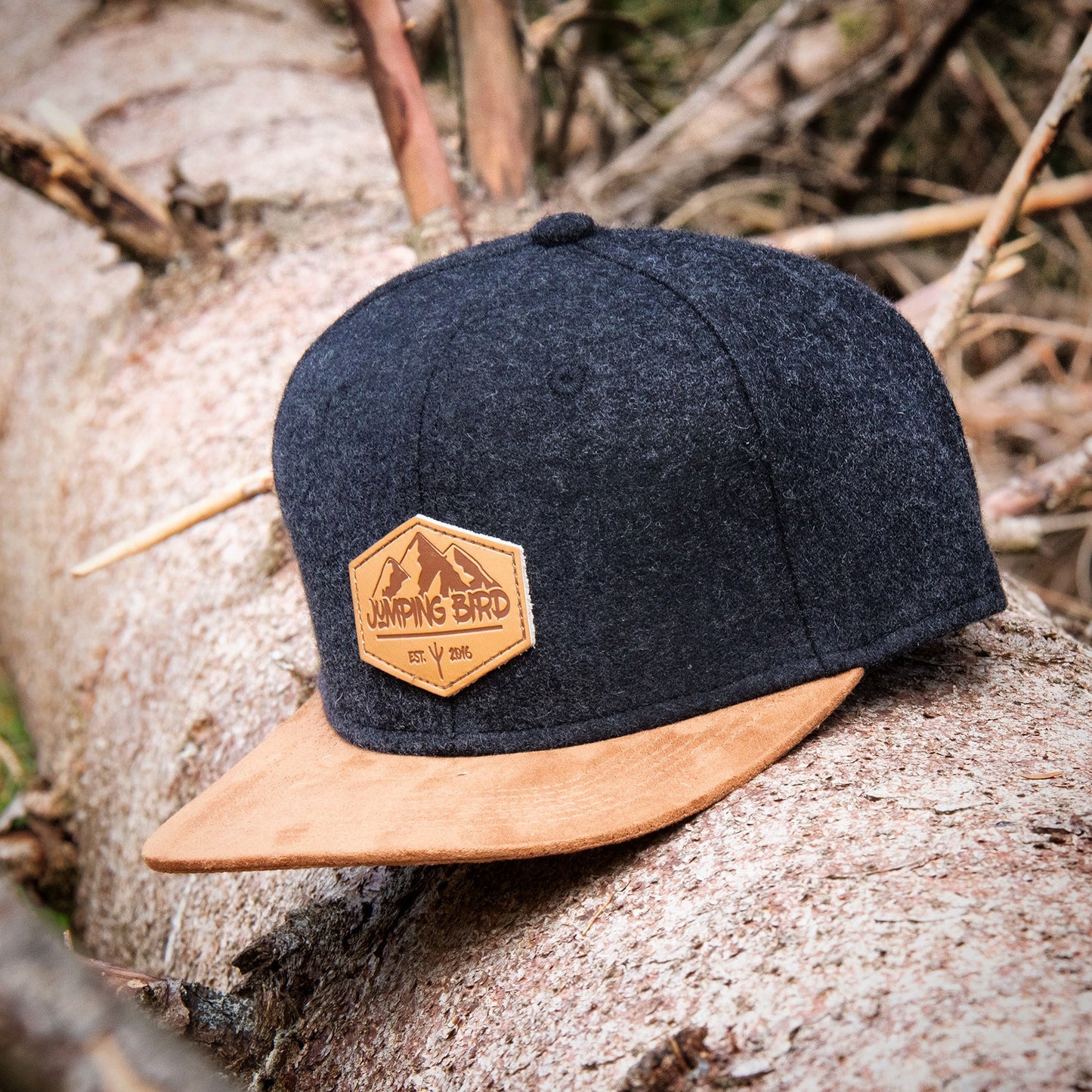 Filz-Snapback von Jumping Bird in Anthrazit-Braun mit geprägtem Lederoptik-Patch vorn und seitlichem Logostick