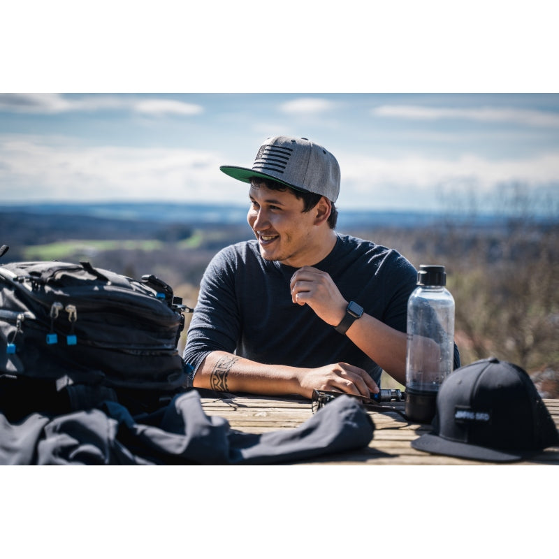 Snapback-Cap von Jumping Bird in Hellgrau-Schwarz mit gesticktem Flaggen-Design vorn, Logostick seitlich und grünem Schirm
