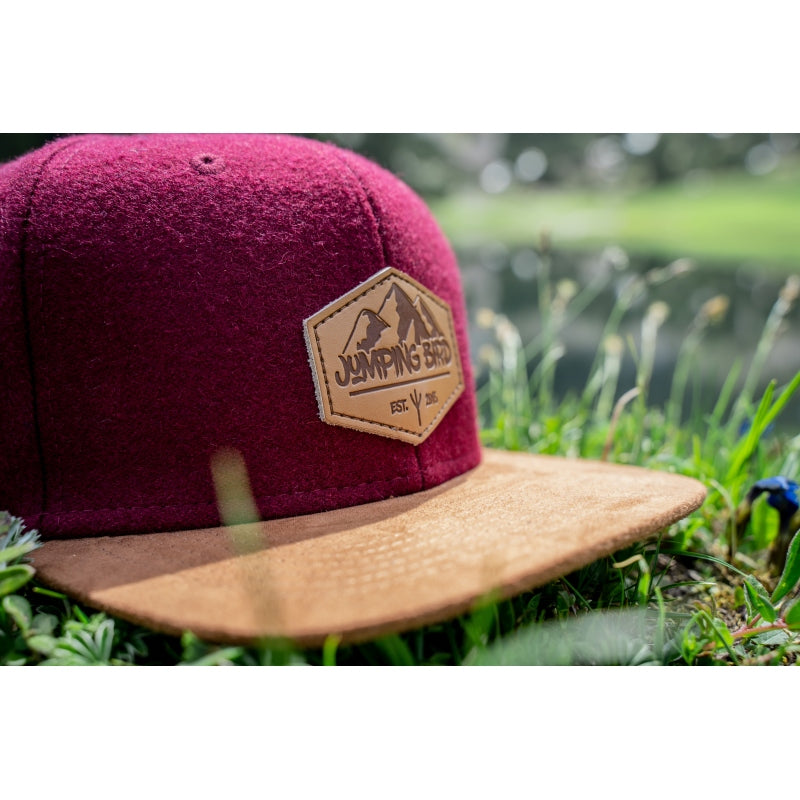 Filz-Snapback von Jumping Bird in Dunkelrot-Braun mit geprägtem Lederoptik-Patch vorn und seitlichem Logostick