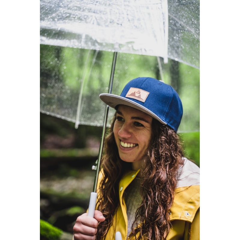 Snapback-Cap von Jumping Bird in Blau-Grau mit geprägtem Lederoptik-Patch vorn und seitlichem Logostick