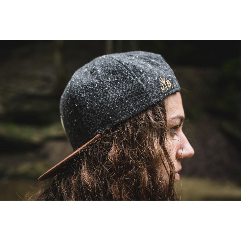 Snapback-Cap von Jumping Bird in Dunkelgrau-Braun mit geprägtem Lederoptik-Patch vorn und seitlichem Logostick