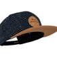 Snapback-Cap von Jumping Bird in Anthrazitblau-Braun mit geprägtem Lederoptik-Patch vorn und seitlichem Logostick