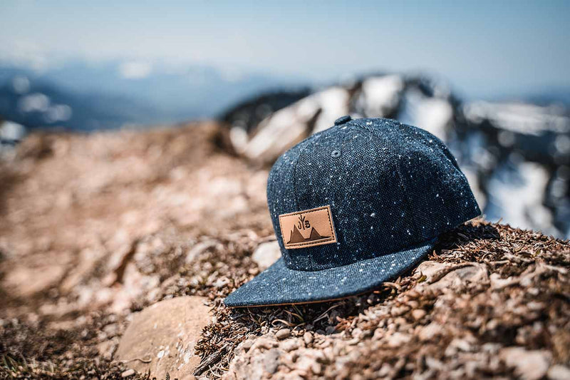Snapback Cap von Jumping Bird - Modell Eiger in anthrazitblau meliert mit Patch in Lederoptik und Logo-Stick seitlich