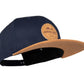 Snapback-Cap von Jumping Bird in Ozeanblau-Braun mit geprägtem Lederoptik-Patch vorn und seitlichem Logostick