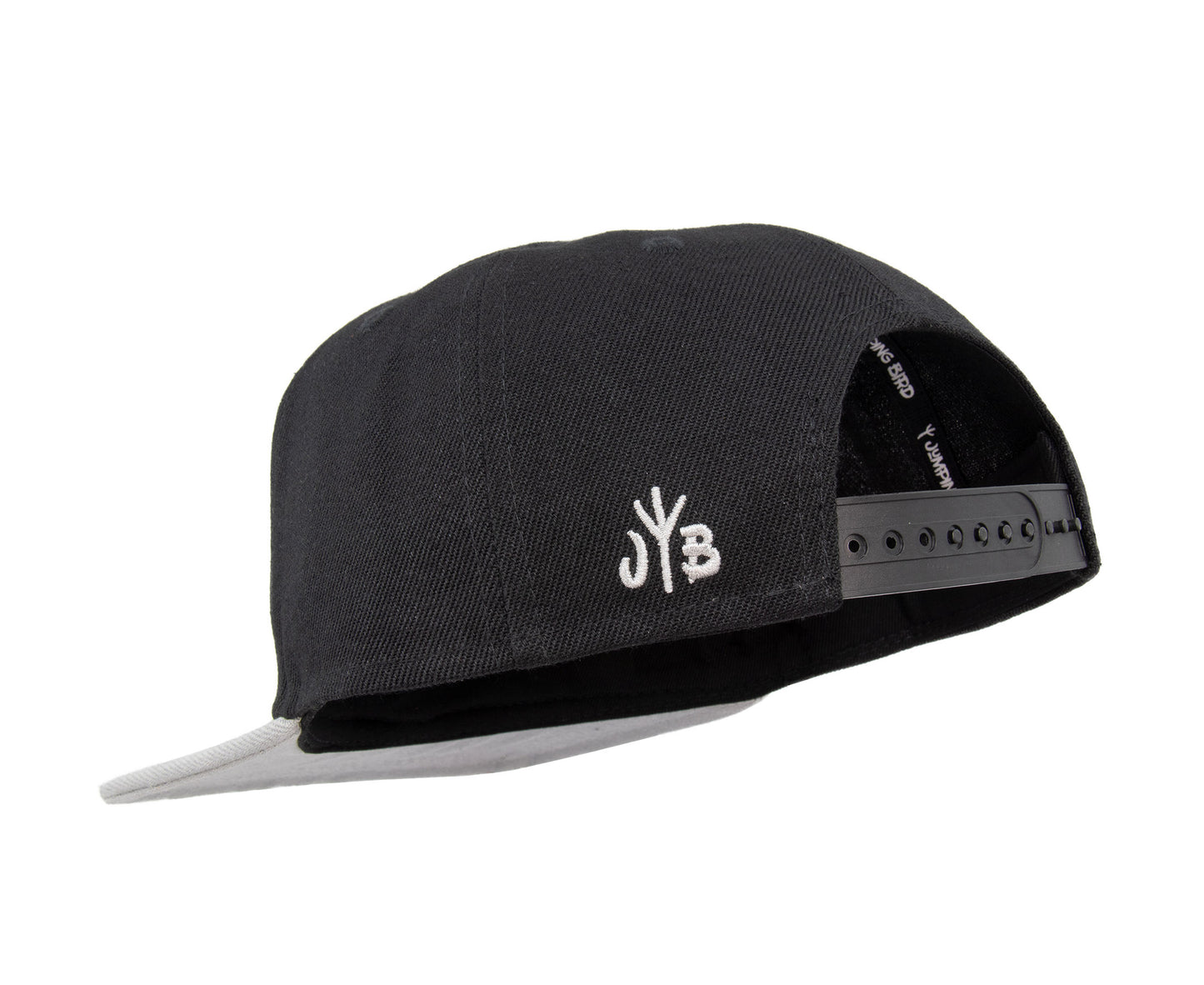 Snapback-Cap von Jumping Bird in Schwarz-Grau mit geprägtem Lederoptik-Patch vorn und seitlichem Logostick