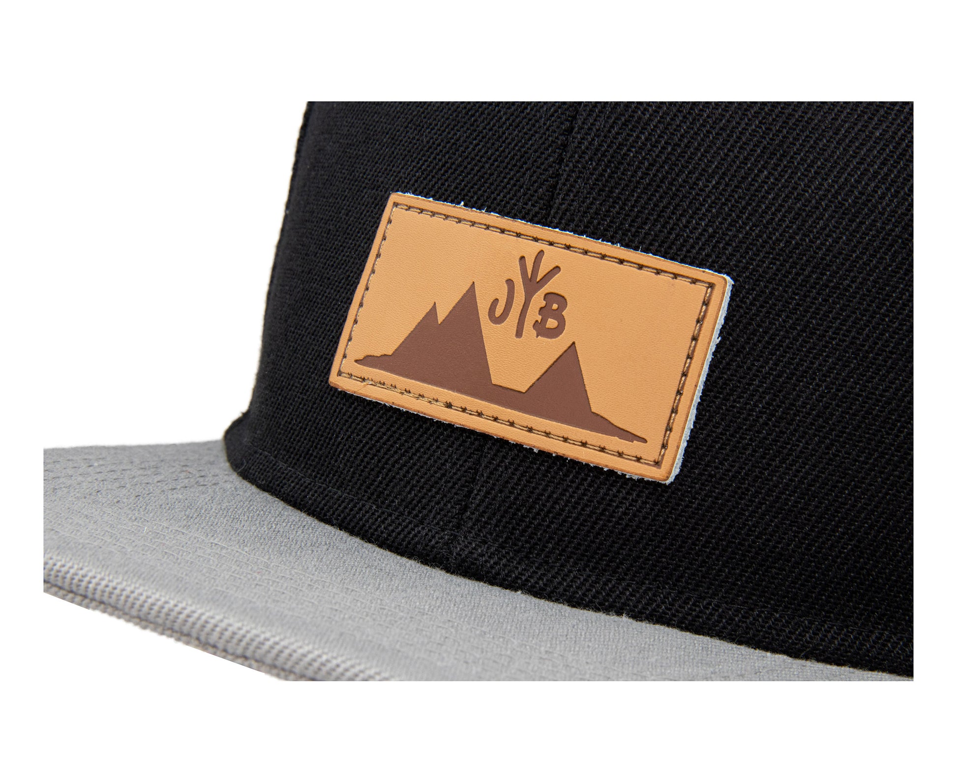 Snapback-Cap von Jumping Bird in Schwarz-Grau mit geprägtem Lederoptik-Patch vorn und seitlichem Logostick