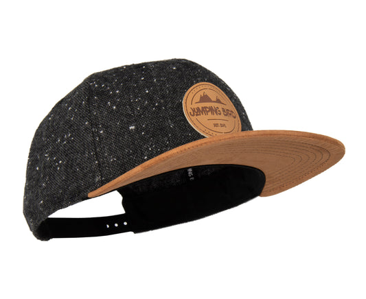 Snapback-Cap von Jumping Bird in Dunkelgrau-Braun mit geprägtem Lederoptik-Patch vorn und seitlichem Logostick