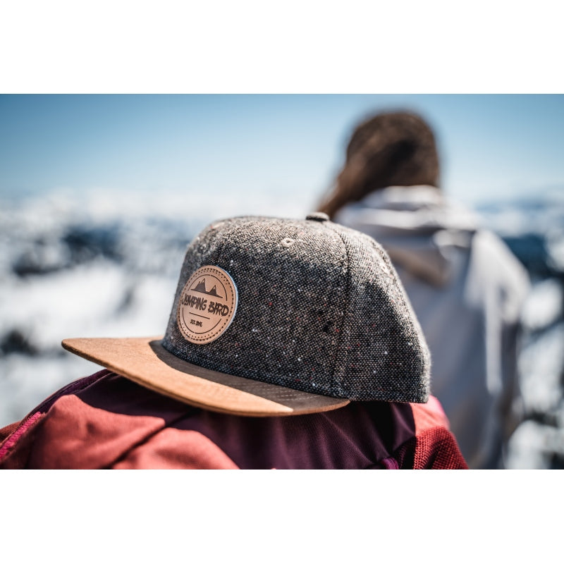 Snapback-Cap von Jumping Bird in Tweed-Braun mit geprägtem Lederoptik-Patch vorn und seitlichem Logostick