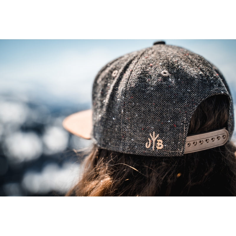 Snapback-Cap von Jumping Bird in Tweed-Braun mit geprägtem Lederoptik-Patch vorn und seitlichem Logostick