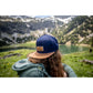Snapback-Cap von Jumping Bird in Blau-Braun mit geprägtem Lederoptik-Patch vorn und seitlichem Logostick