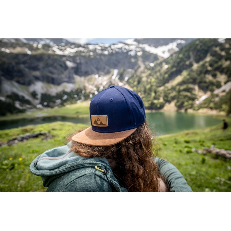 Snapback-Cap von Jumping Bird in Blau-Braun mit geprägtem Lederoptik-Patch vorn und seitlichem Logostick