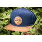 Snapback-Cap von Jumping Bird in Ozeanblau-Braun mit geprägtem Lederoptik-Patch vorn und seitlichem Logostick