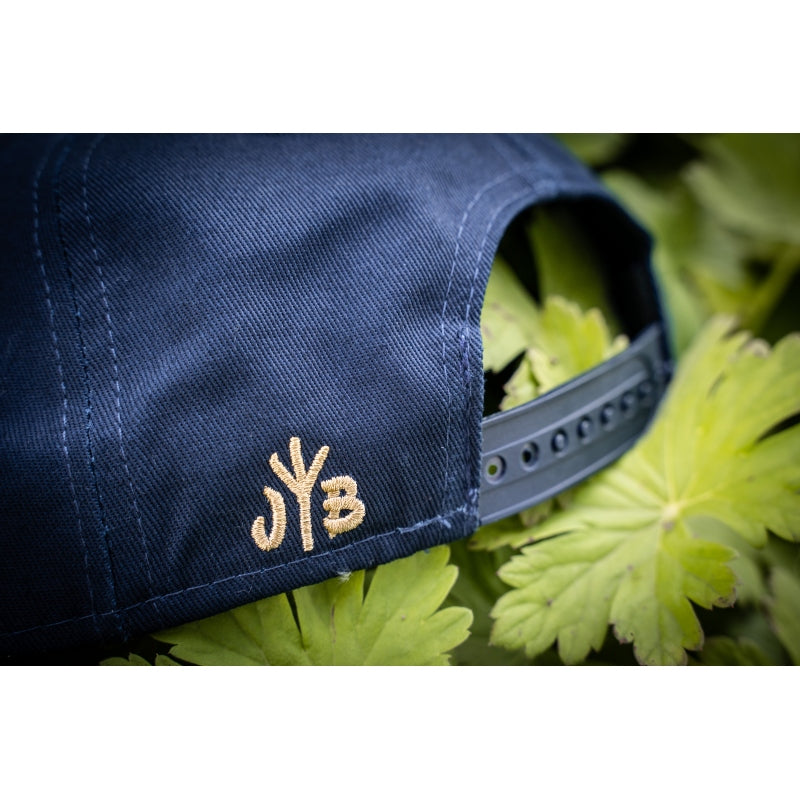 Snapback-Cap von Jumping Bird in Ozeanblau-Braun mit geprägtem Lederoptik-Patch vorn und seitlichem Logostick