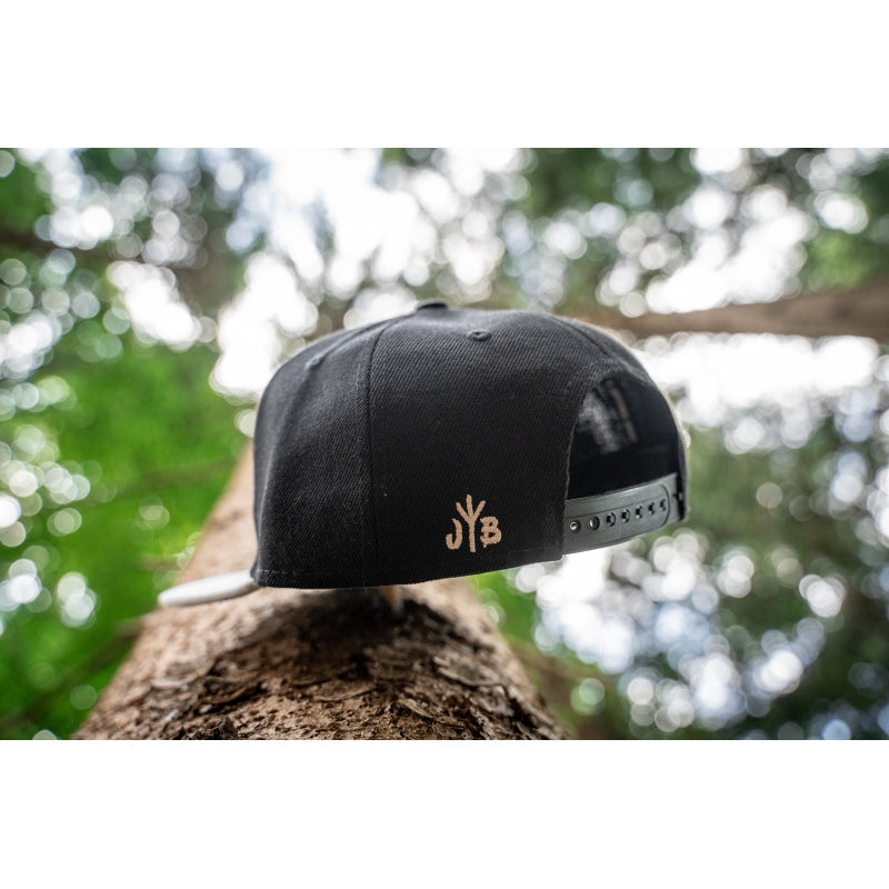 Snapback-Cap von Jumping Bird in Schwarz-Grau mit geprägtem Lederoptik-Patch vorn und seitlichem Logostick