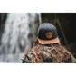 Snapback-Cap von Jumping Bird in Dunkelgrau-Braun mit geprägtem Lederoptik-Patch vorn und seitlichem Logostick
